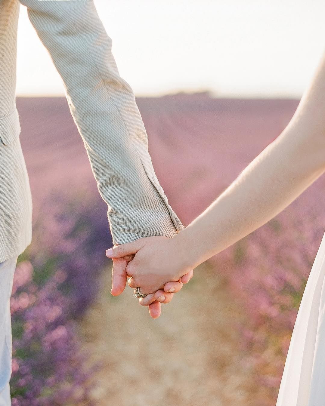 Mains d’un couple de mariés dans un champ de lavande